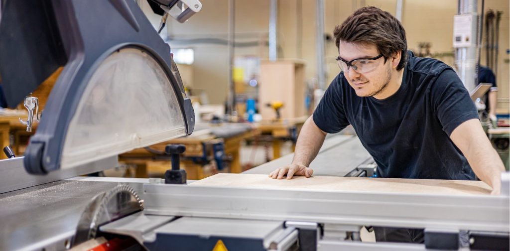 Attestations AEC Photo d'un élève glissant une planche de bois vers une machine