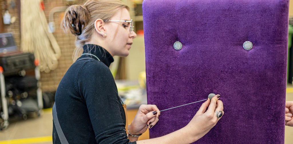 Professionnels DEP Photo d'une élève ajoutant un bouton sur le dossier mauve d'une chaise rembourrée