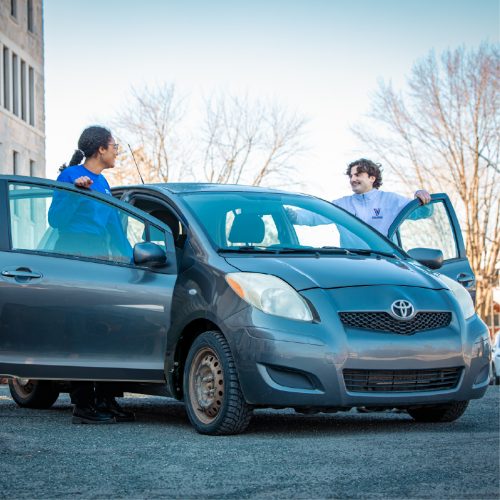 photo d'une voiture avec deux élèves qui embarquent chaque côté