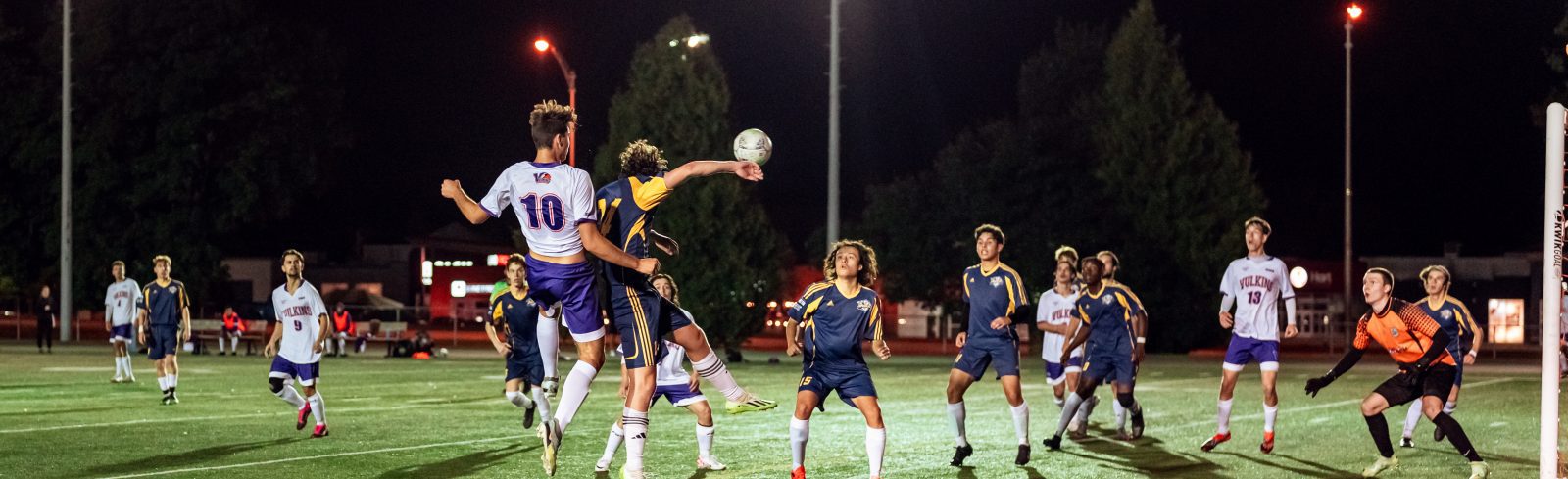 photo d'action d'un match de soccer masculin montrant des athlètes se disputant un ballon aérien