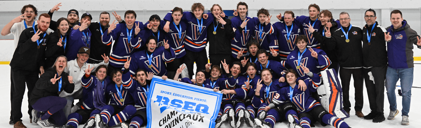 Photo entête d'équipe montrant les joueurs des Vulkins hockey qui célèbrent avec la bannière de champions provinciaux 2025-2026