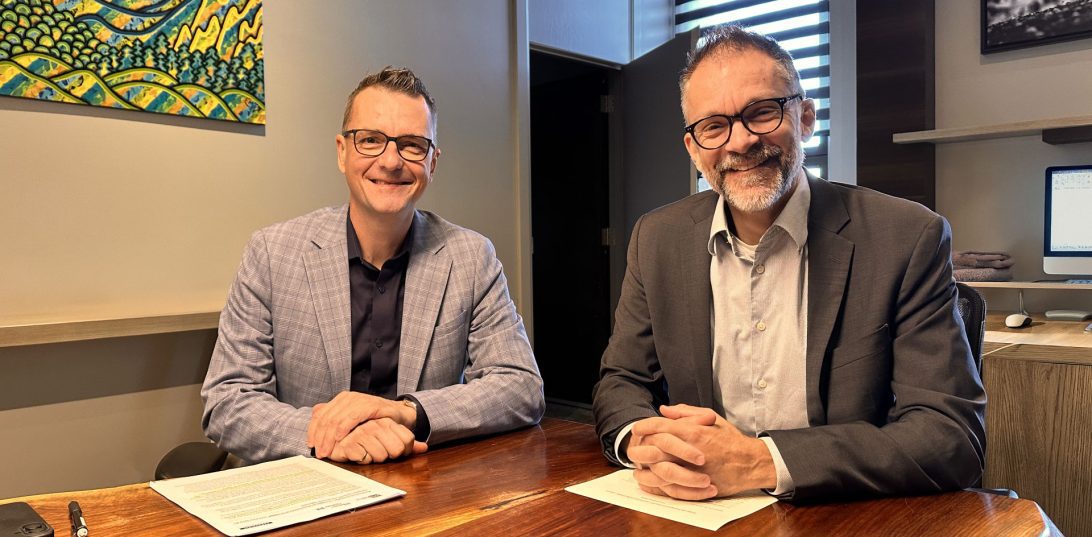 Photo de deux hommes d'affaire, Frederick Gagnon et Denis Deschamps, assis autour d'une table dans un bureau.