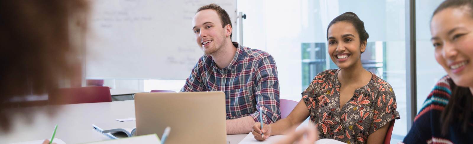 photo où on voit trois personnes assises à une table écoutant une autre personne que l'on voit de dos